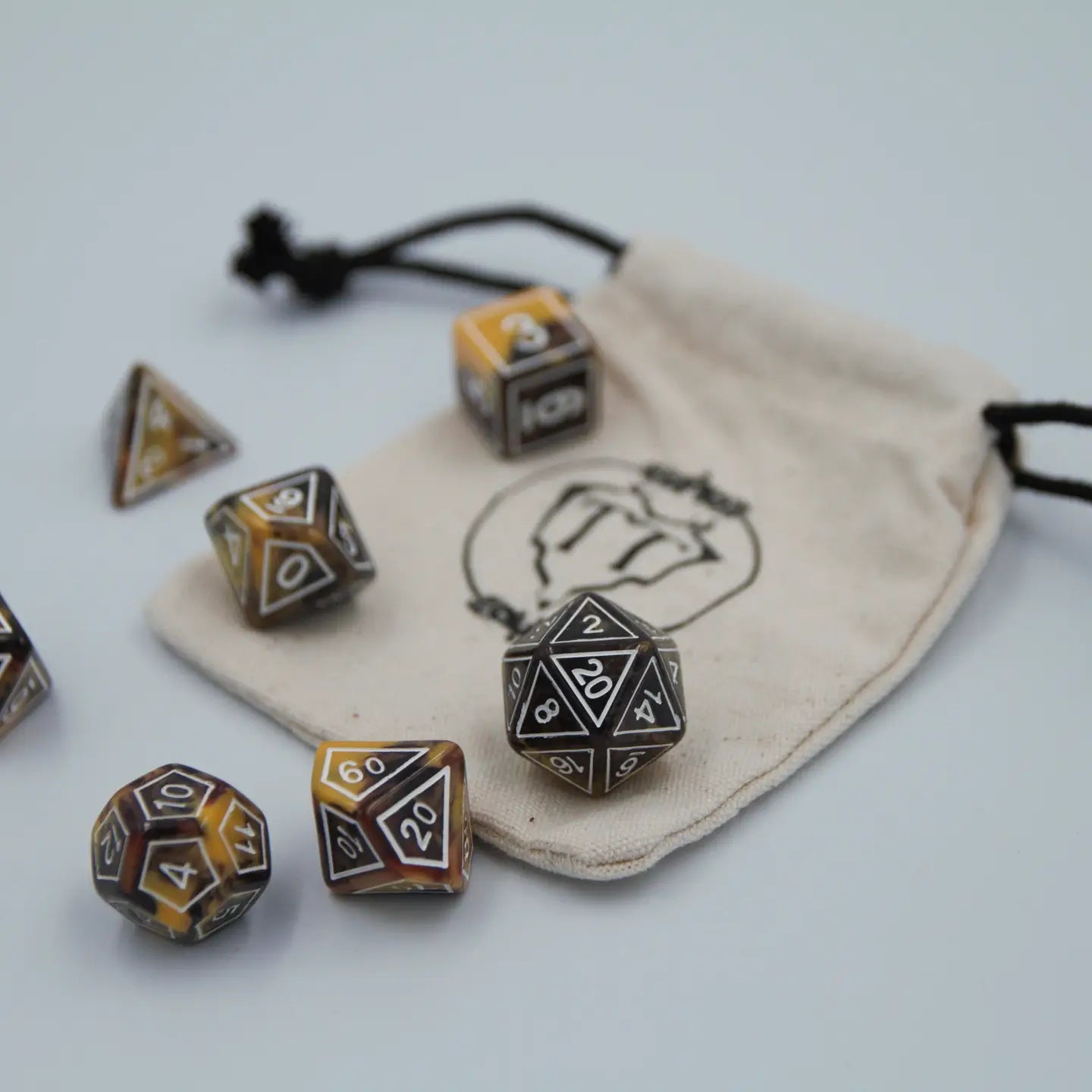 Set of polyhedral dice with a drawstring bag on a light background